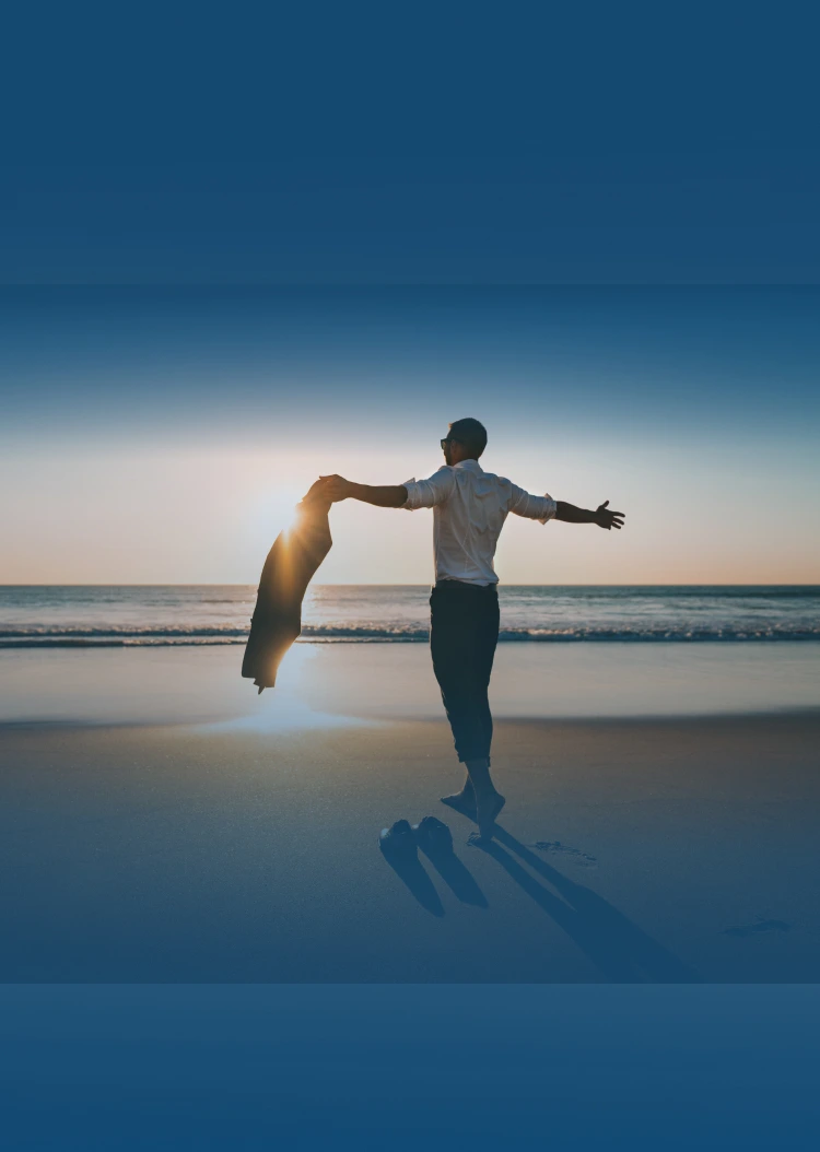 A man by the sea is taking off his business suit.